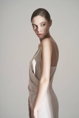 Zarif, şık elbiseli bir kadın. Stüdyoda akşam kıyafetleri içinde güzel bir poz. Klasik ipek elbise. Seksi bayan beyaz arka planda kalsın. Klasik saç stili ve makyajlı mükemmel bir genç kadın.. 