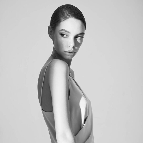 Woman in elegant fashionable dress. Beautiful model pose in studio in evening clothes. Classic silk dress. Sexy lady stay on white background. Perfect young woman with classic hairstyle and makeup. 