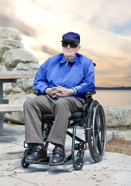 Oudere senior man in de rolstoel zitten buiten — Stockfoto