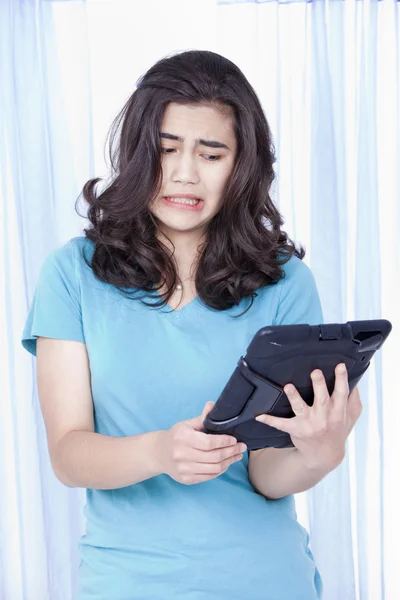 Ragazza adolescente guardando con disgusto tablet computer in mano — Foto Stock