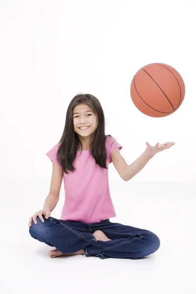 Niña asiática de diez años sosteniendo baloncesto, aislada en blanco — Foto de Stock