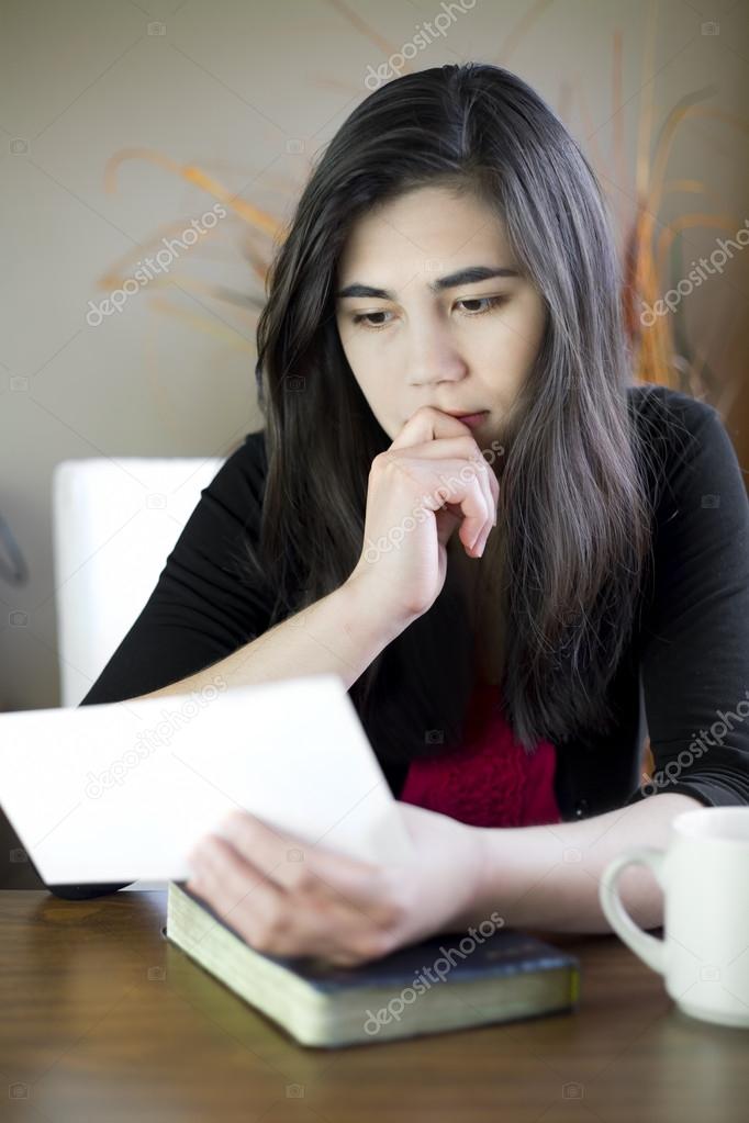 Teenage girl or young woman reading a note, worried expression