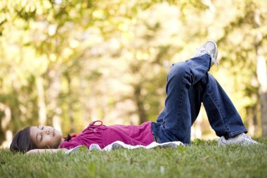 Küçük kız çimenlerde yatıyor.