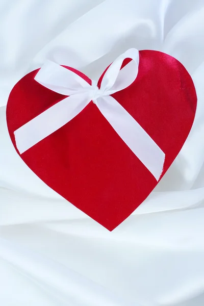 Red heart with ribbon on white satin — Stock Photo, Image