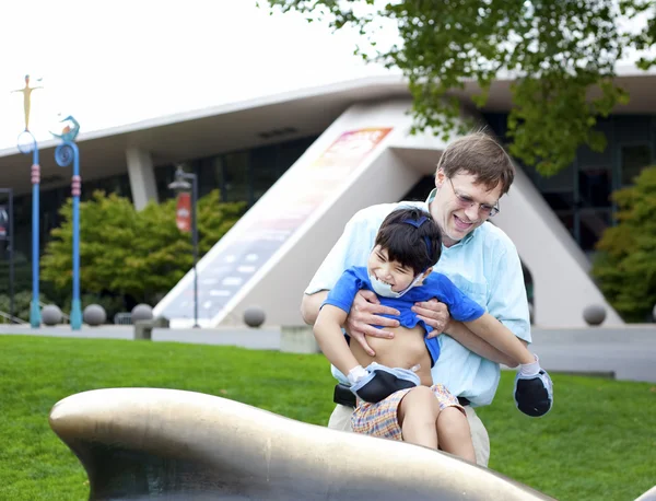 Father helping disabled son play outdoors — Stock Photo, Image