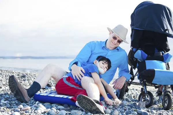 Vater sitzt am Strand und spielt mit behindertem Sohn — Stockfoto