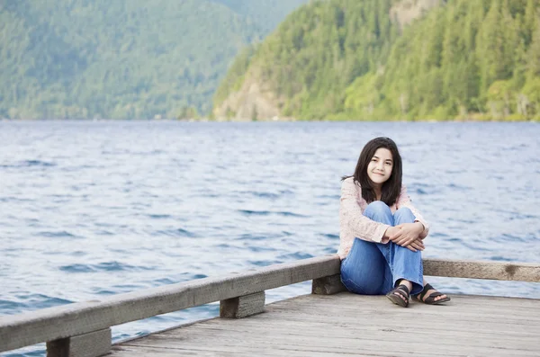 Young teen girl sitting quietly on lake pier, relaxing — Stock Photo, Image