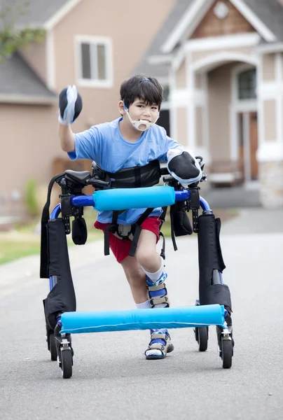 Zes-jarige gehandicapte jongen wandelen in walker in de straat — Stockfoto