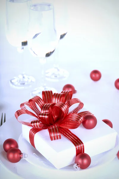 Presente branco com fitas vermelhas em um prato de jantar, Natal eles — Fotografia de Stock