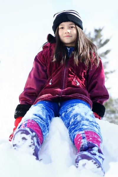Kışın kar yığını üzerinde oturan kız — Stok fotoğraf