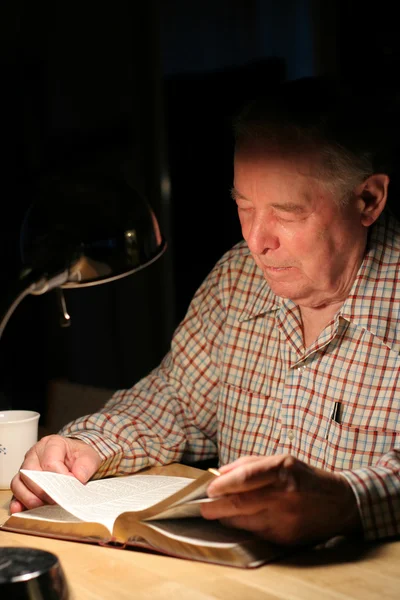 Homme âgé lisant la Bible avec lampe la nuit — Photo