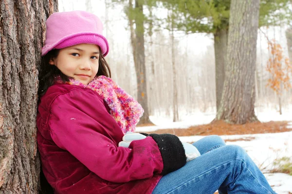 Barnet sitter under träd utomhus på vintern — Stockfoto