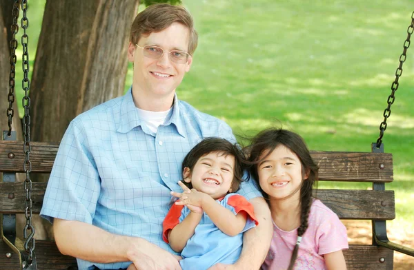 Father and children enjoying swinging in the park — Stock Photo, Image