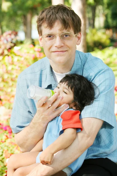 Vader voeden van baby een fles in het park — Stockfoto