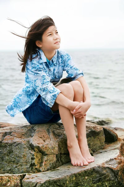 Nine year old girl sitting by lake — Stock Photo, Image