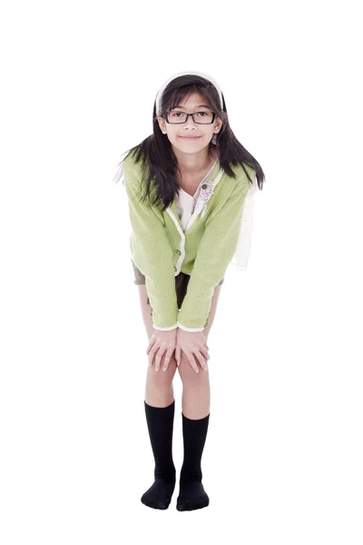 Menina em camisola verde e óculos dobrando para a frente, mão sobre joelhos — Fotografia de Stock