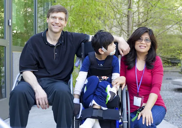 Enfant handicapé en fauteuil roulant avec ses parents — Photo