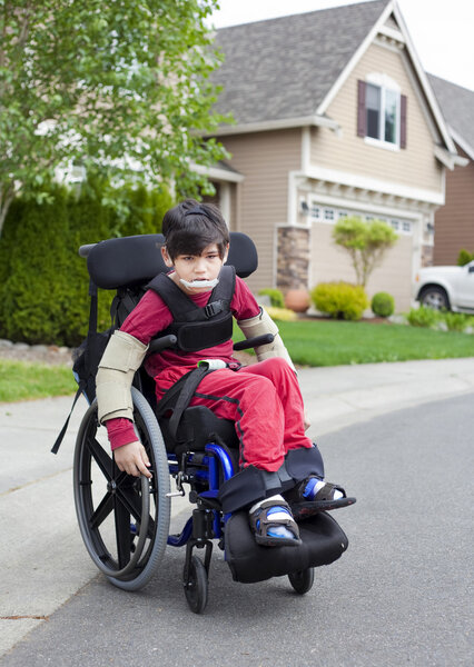Disabled little boy in wheelchair outdoors