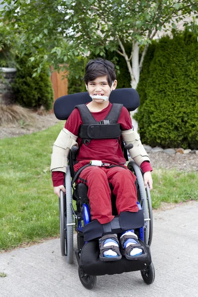 Мальчик-инвалид в инвалидной коляске на открытом воздухе — стоковое фото