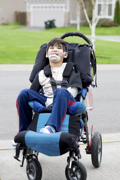 Happy little disabled boy in wheelchair