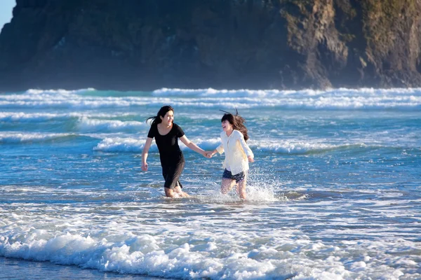 Две сестры бегут по океанским волнам вместе — стоковое фото