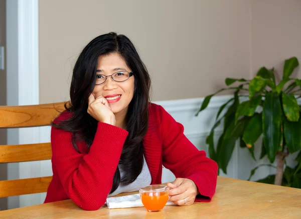 Aziatische vrouw in vroege jaren veertig zitten aan tafel met drankje — Stockfoto