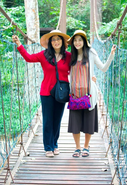 Asian mother and daughter standing on wooden hanging bridge in f — Stock Photo, Image