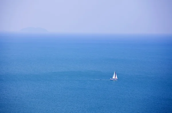 Beautiful blue ocean with white sailboat near horizon