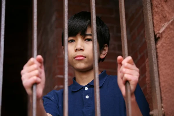 Boy standing behind bars — Stock Photo, Image