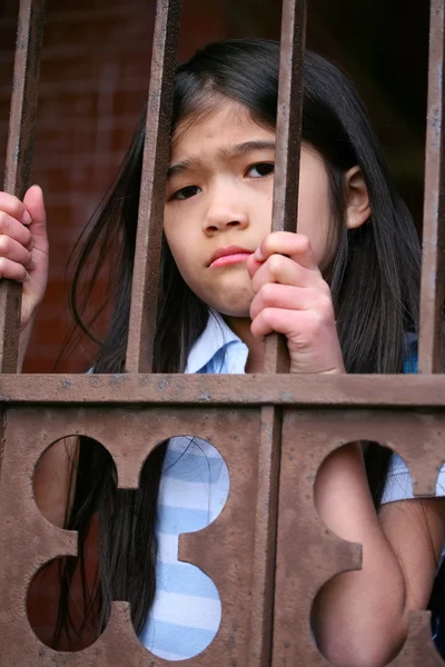 Niña parada entre rejas de hierro —  Fotos de Stock