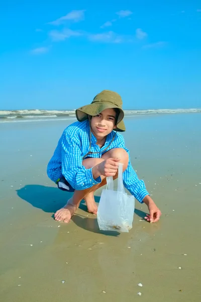 Young biracial Asian boy Looking for seashells on beach — Stock Photo, Image