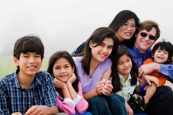 Multiracial family of seven sitting on beach — Stock Photo, Image