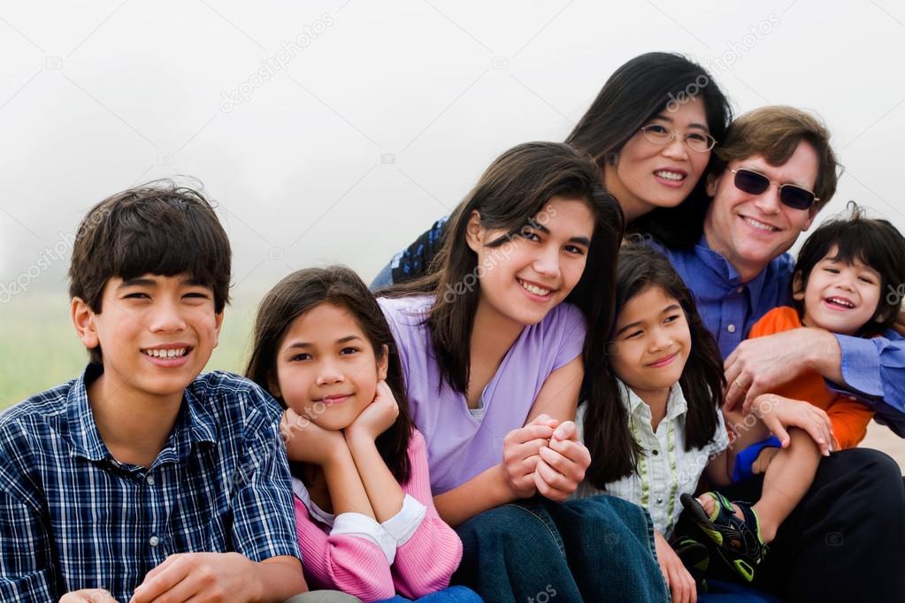 Multiracial family of seven sitting on beach