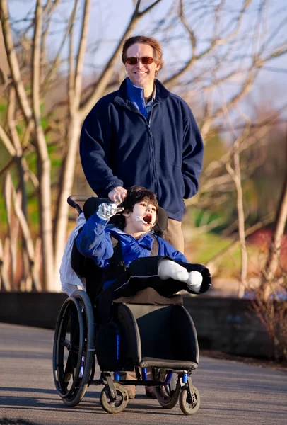 Père marchant avec un fils handicapé en fauteuil roulant — Photo