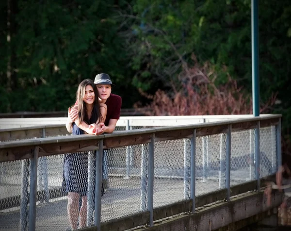 Joven pareja interracial de pie en puente sobre el agua —  Fotos de Stock