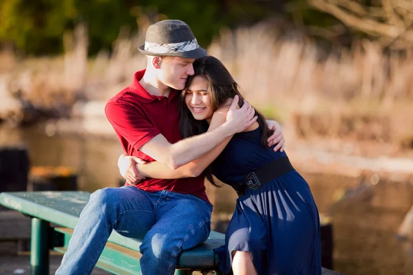 Young interracial couple sitting together on dock over lake — Stock Photo, Image