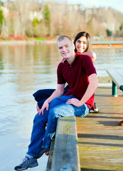 Beautiful interracial couple sitting on wooden dock over lake — Stock Photo, Image