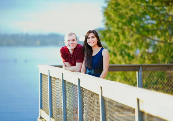 Joven pareja interracial de pie juntos en el muelle de madera overlo —  Fotos de Stock