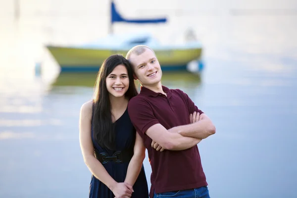 Happy young interracial couple standing together by lake — Stock Photo, Image
