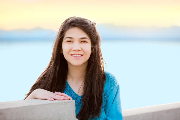 Beautiful young teen girl enjoying outdoors by lake at sunset — Stock Photo, Image