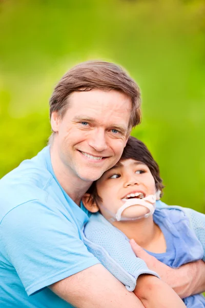 Yakışıklı baba gülümseyerek tutarak açık havada oğlu devre dışı. — Stok fotoğraf