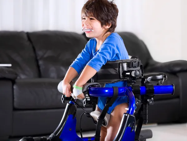 Disabled biracial boy in medical walker. Living room setting. — Stock Photo, Image