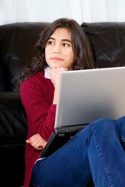 Biracial tonåring flicka sitter mot soffan med laptop — Stockfoto