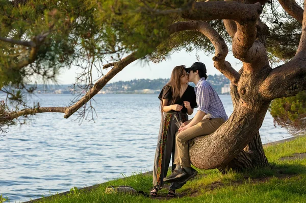 Young Biracial Couple Sitting Large Tree Branch Next Water Leaning — Stock Photo, Image