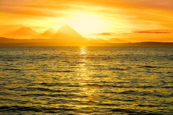 小さな波と青い海の上の曇りの夜のオレンジと黄色の夕日 — ストック写真