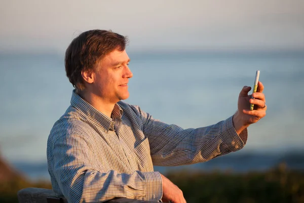 Kaukaski Mężczyzna Rozmawiający Smartfonie Podczas Relaksu Nad Oceanem Zachodzie Słońca — Zdjęcie stockowe