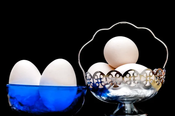 Uova bianche in ciotola di vetro, cesto, illuminato frontalmente, isolato, bac nero — Foto Stock