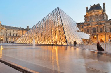 Paris, Fransa - 18 Kasım 2021: Alacakaranlıkta Piramit ile Louvre Müzesi manzarası. Burası Fransa 'nın en popüler seyahat merkezlerinden biri ve Paris' in merkezi bir simgesidir..