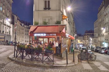 Paris, Fransa - 12 Kasım 2021: Paris, Fransa 'da Montmartre' nin eski sokakları. Parisliler ve turistler Fransız Kafe 'sinde yiyecek ve içeceklerin keyfini çıkarıyorlar..