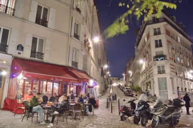 Paris, Fransa - 12 Kasım 2021: Paris, Fransa 'da Montmartre' nin eski sokakları. Parisliler ve turistler Fransız Kafe 'sinde yiyecek ve içeceklerin keyfini çıkarıyorlar..